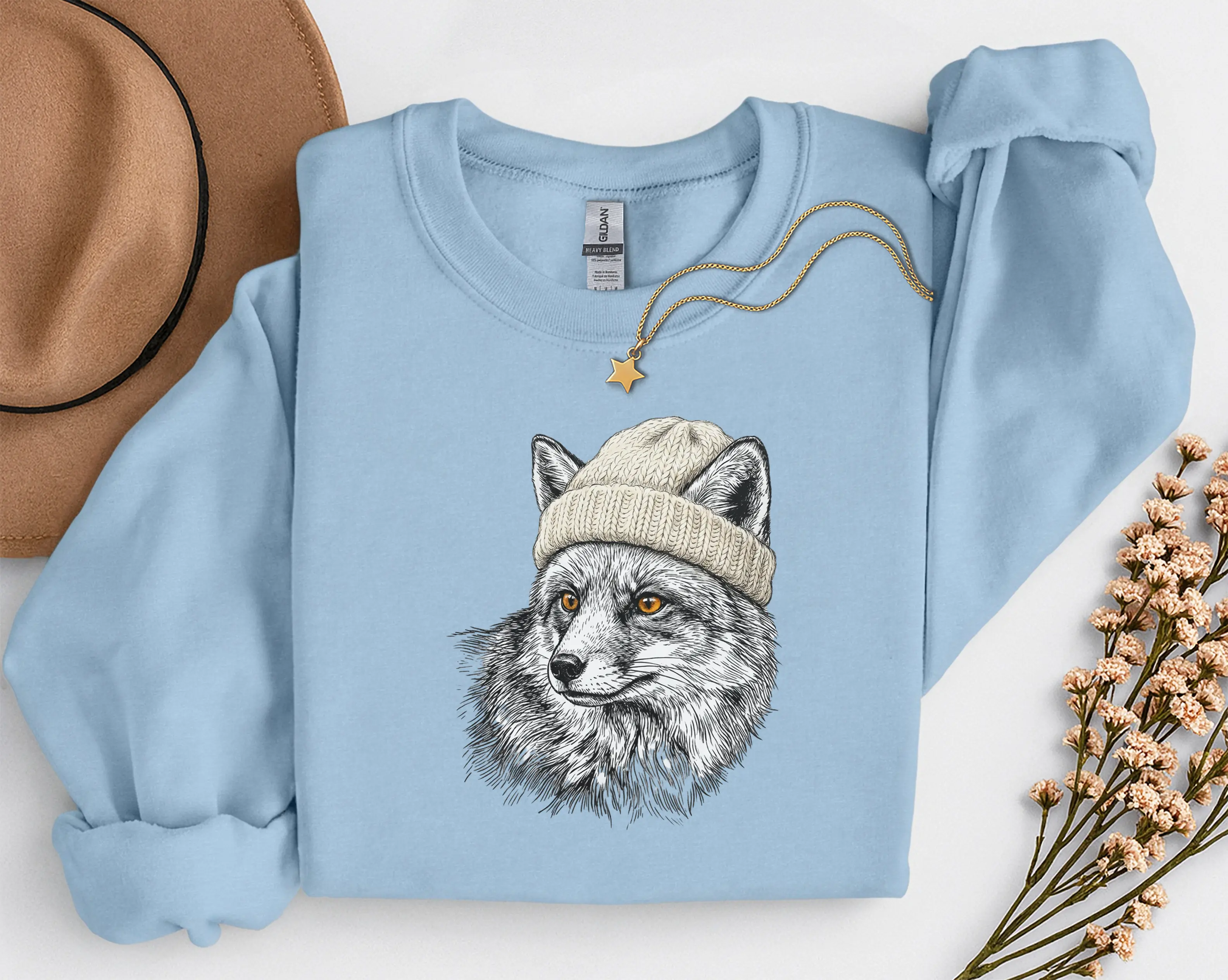 sweat-renard-bonnet-lightblue Sweat bleu clair avec illustration d'un renard en bonnet, photo à plat avec chapeau et collier étoile