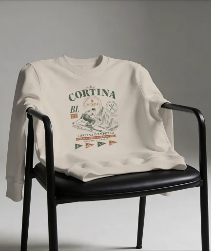 Sweat Cortina d'Ampezzo vintage sable posé sur chaise, design skieur illustré JO 1956