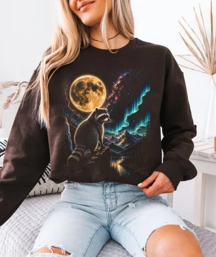 Mannequin femme portant le sweat-shirt graphique marron avec le motif de raton laveur et lune dans un style décontracté.