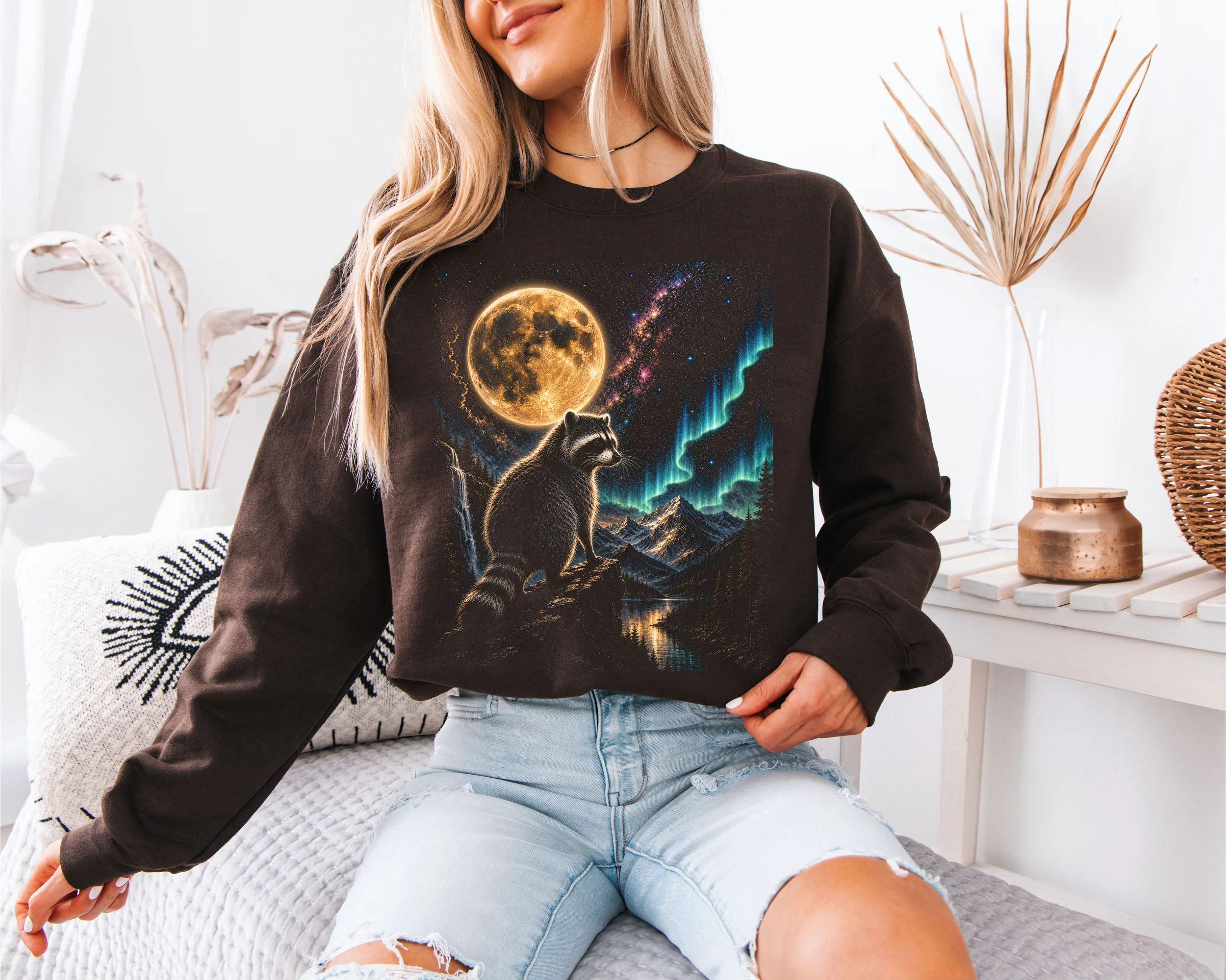 Mannequin femme portant le sweat-shirt graphique marron avec le motif de raton laveur et lune dans un style décontracté.